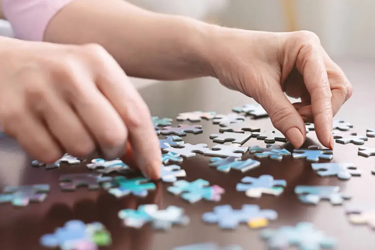Dwie dłonie układają puzzle. Czy jestem inteligentny? Ta czynność wymaga skupienia i logicznego myślenia.
